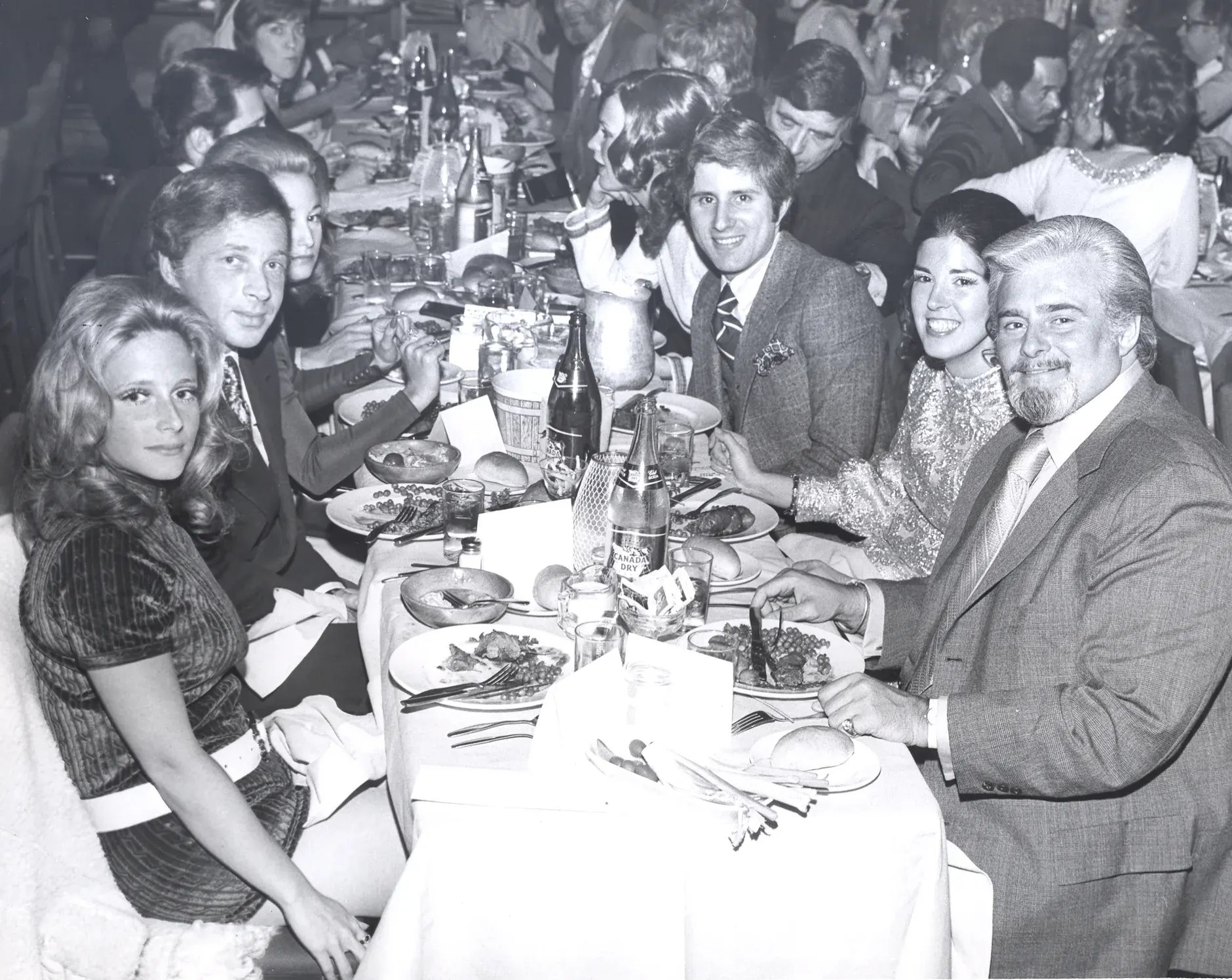 Marie Fisher, in the foreground, at a long banquet table of young guests turning toward the camera over dinner.