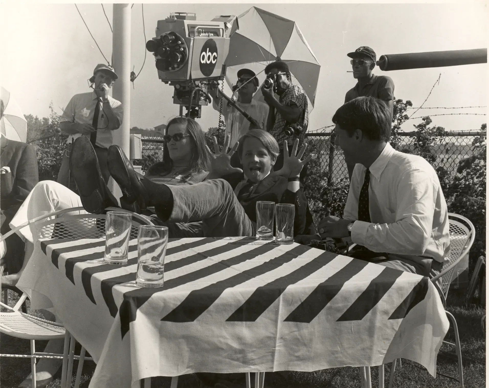 Edsel Ford II, sixteen years old, hands raised at a striped terrace table beneath an ABC television camera on the riverfront.