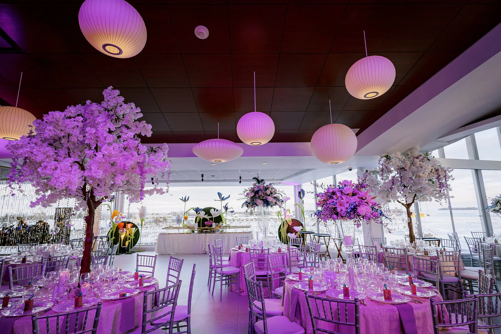 Wedding reception set with cherry blossom centerpieces and purple uplighting